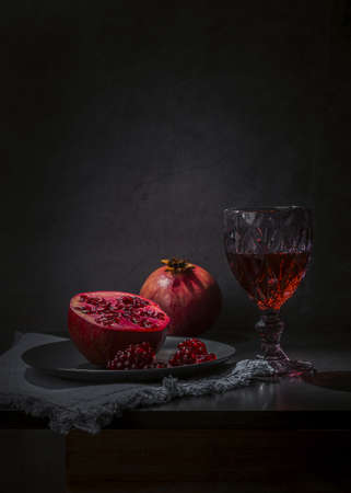 Red wine in a glass and pomegranate on a dark background.の写真素材