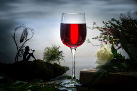 Red wine in a glass and a fabulous decoration with a forest fairy.の写真素材