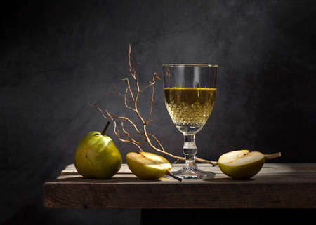 White wine in a glass and pears on a dark background.の写真素材