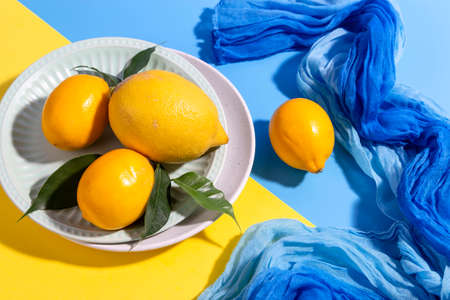 Fresh lemons on a plate on a bright background. copyspace.の写真素材