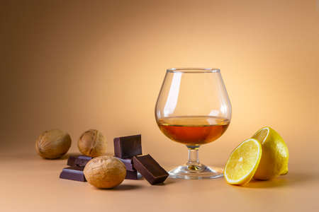 A glass of cognac and pieces of chocolate on a bright background. copyspace.の写真素材