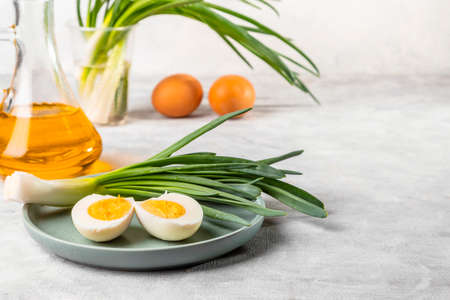 Fresh green onions, boiled eggs and vegetable oil on a light background. Simple and healthy breakfast. copyspace.の写真素材
