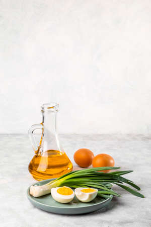 Fresh green onions, boiled eggs and vegetable oil on a light background. Useful breakfast. copyspace.の写真素材