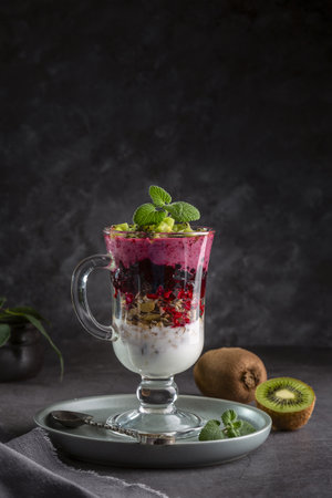 Yogurt smoothie with granola, black currant and kiwi pieces. Delicious and healthy breakfast. copyspace.の写真素材