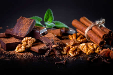 A pile of dark broken chocolate sprinkled with cocoa powder, nuts and spices. copyspace.の写真素材
