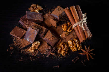 A pile of dark broken chocolate sprinkled with cocoa powder, nuts and spices. copyspace.の写真素材
