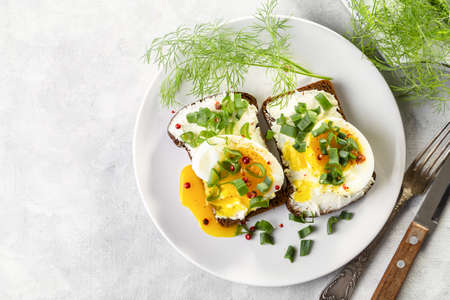 Sandwich with curd cheese, boiled egg and green onions, sprinkled with pink pepper on a light...