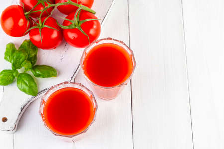 Fresh tomato juice, tomatoes and basil on a light wooden background. copyspace.の写真素材