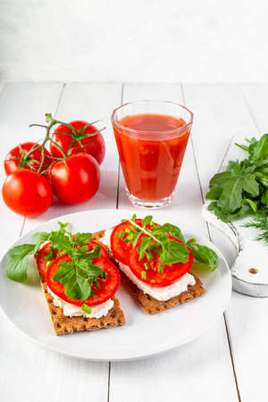 Crispbread with curd cheese, tomatoes, green onions, arugula and basilica. Delicious and healthy breakfast.の写真素材