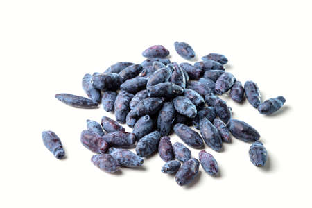Honeyberry (Lonicera caerulea). Heap of honeysuckle sweet berry (honeysuckle berries) on a white...