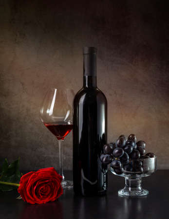 Wine, grapes and red rose on a dark background.の写真素材