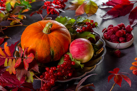 Pumpkin, apples and berries with autumn leaves on a textured table.の写真素材