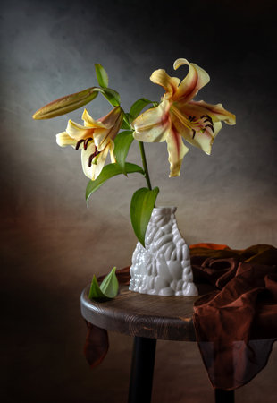 Still life with lilies in a porcelain vase on a wooden table.の写真素材