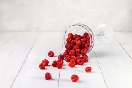 Fresh raspberries in a glass on a wooden table. copyspace.