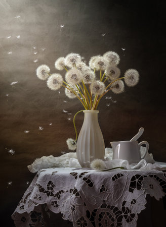 A bouquet of fluffy dandelions on a coffee table on a dark background.の写真素材