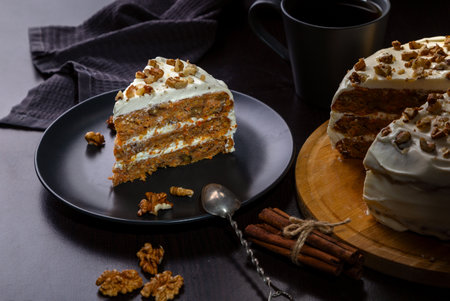 Carrot cake with butter cream and walnuts on a dark background.の写真素材