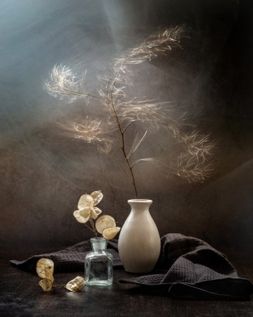 Modern still life with dried plants in a vase on a dark background. Wind and movement in the frame.の写真素材