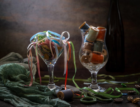 Modern still life with spools of multi-colored threads and satin ribbons on a dark background.の写真素材