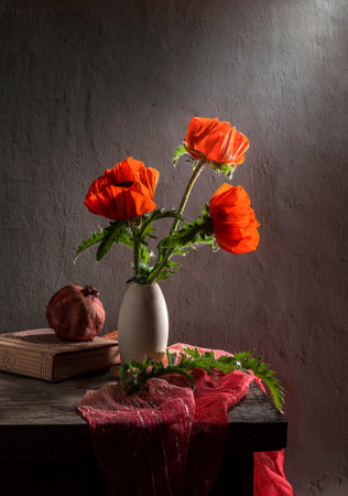 Modern still life with poppies in a clay vase and pomegranate on a dark background.の写真素材