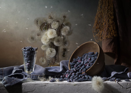 Country still life with dandelions and scattered honeysuckle on a dark background.の写真素材