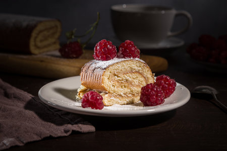 Roll with fresh raspberries on a dark background.