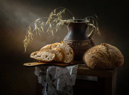 Still life with bread and cereals in a clay jug on a dark background.の写真素材