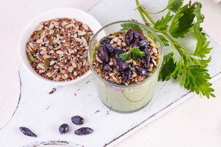 Healthy eating, lifestyle, veganism, alkaline diet, vegetarian concept. Green smoothies from nettle and yogurt, with honey, bran, seed mix and honeysuckle. Garnished with a mint leaf.の写真素材