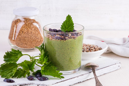 Healthy eating, lifestyle, veganism, alkaline diet, vegetarian concept. Green smoothies from nettle and yogurt, with honey, bran, seed mix and honeysuckle. Garnished with a mint leaf.の写真素材