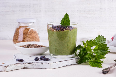 Healthy eating, lifestyle, veganism, alkaline diet, vegetarian concept. Green smoothies from nettle and yogurt, with honey, bran, seed mix and honeysuckle. Garnished with a mint leaf.の写真素材