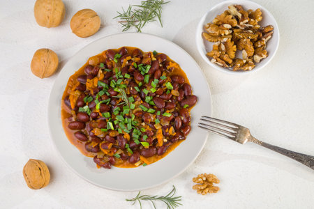 Red beans in tomato sauce with green onions and walnuts. Lenten vegetarian food.の写真素材
