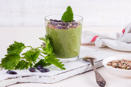 Healthy eating, lifestyle, veganism, alkaline diet, vegetarian concept. Green smoothies from nettle and yogurt, with honey, bran, seed mix and honeysuckle. Garnished with a mint leaf.の写真素材