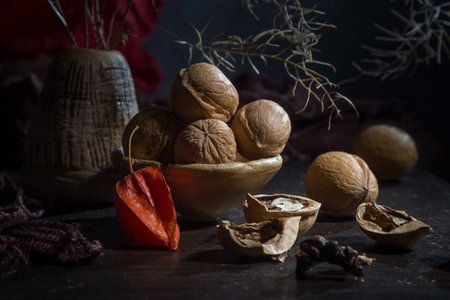 Contemporary still life with dry branches, physalis and walnuts on a dark background.