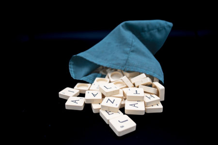 scrabble letter tiles coming out of a green bag. black backgroundのeditorial素材