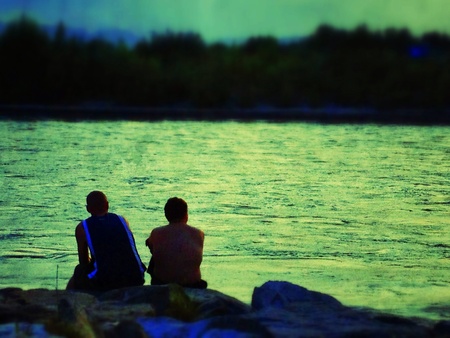 Two men sitting beside a lakeの素材