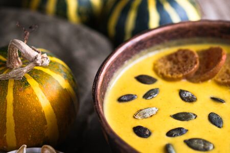 Homemade pumpkin soup with seeds, spices, herbs and croutons on a rustic background copy spaceの写真素材