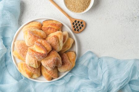 Cookies with cottage cheese and sugar on a light plate on a light background with a blue napkin free...