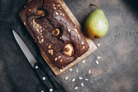 Homemade pastries. Chocolate cake with pear and cinnamon on a dark background top view copy space.の写真素材
