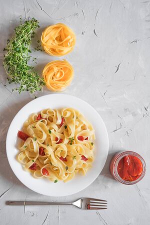 Italian traditional pasta tagliatelle with dried tomatoes and thyme on a light background copy space top viewの写真素材