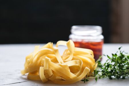Italian traditional pasta tagliatelle with dried tomatoes and thyme on a light background.の写真素材