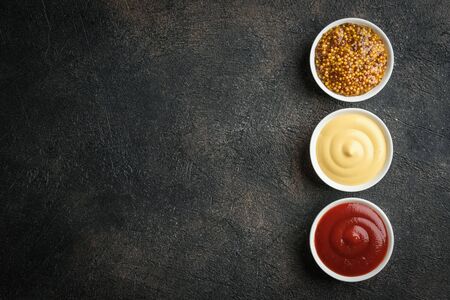 Set of popular sauces - mustard, ketchup and mayonnaise on a dark background. Top view free copy space.の写真素材