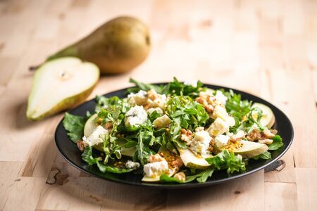 Salad of pear, blue cheese, arugula and nuts with spicy dressing on a wooden background. Healthy eating.の写真素材