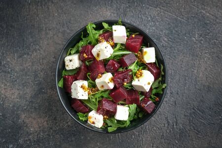 Salad with beetroot, feta cheese, arugula and spicy dressing on a dark background top view. Healthy food. Top view. Copy space.の写真素材