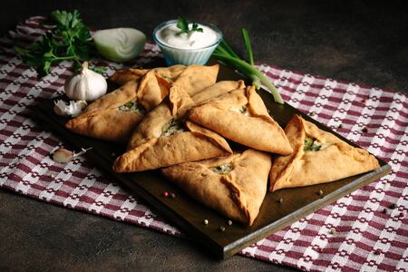 Triangle meat or chicken  pie with potatoes, sour cream, onions, garlic and spices on a dark...