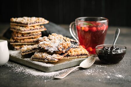 Homemade shortcrust fruit pie with crumble and cup of berry tea  on dark background - homemade...