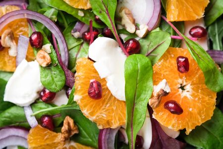 Detox salad with tangerines, mozzarella, herbs, pomegranate seeds and nuts on a dark background. の写真素材