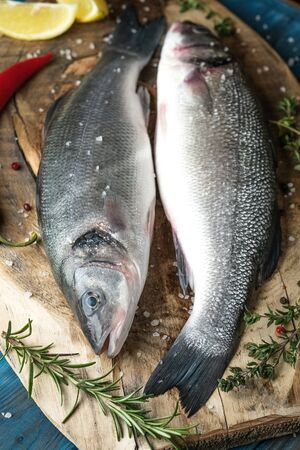 Fresh seabass and ingredients for cooking. Raw fish seabass with lemon, spices and herbs on blue...