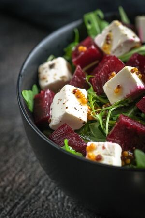 Salad with beetroot, feta cheese, arugula and spicy dressing on a dark background. Healthy food. の写真素材