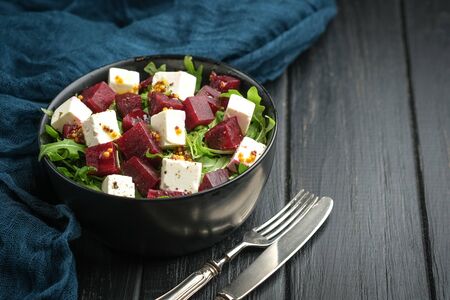 Salad with beetroot, feta cheese, arugula and spicy dressing on a dark background. Healthy food. Top view. Copy space.の写真素材