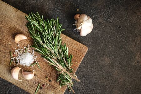 Bunch of fresh rosemary and garlic on a black background.Top view with copy space.の写真素材