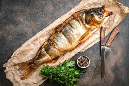 Smoked fish on craft paper with herbs and spices on a dark background.の写真素材